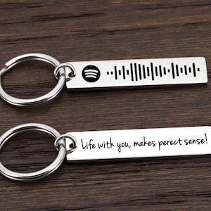 May include: Two silver keychains with a bar-shaped charm. The top charm has a barcode and the text "Life with you, makes perfect sense!" The bottom charm has a barcode and the text "Life with you, makes perfect sense!"