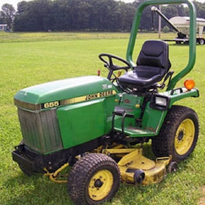 Op de afbeelding: Een groene John Deere 655 gazontractor met een zwarte stoel en een rolbeugel. De tractor heeft een maaidek en een achterkoppeling.