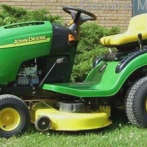 May include: A green and yellow John Deere L100 ride-on lawnmower. The mower features a black steering wheel, a yellow seat, and large black tyres with yellow rims. The John Deere logo is visible on the side of the mower.