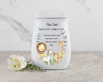 Puede incluir: Urna de cerámica blanca con tapa, que presenta una ilustración de acuarela de un león, una cebra, una jirafa y un zorro en un entorno de bosque. La urna está personalizada con el nombre "Finn Davis" y las fechas "26 de mayo de 2022 - 10 de octubre de 2022". El texto "Te amo todos los días. Y ahora te extrañaré todos los días." también está incluido.