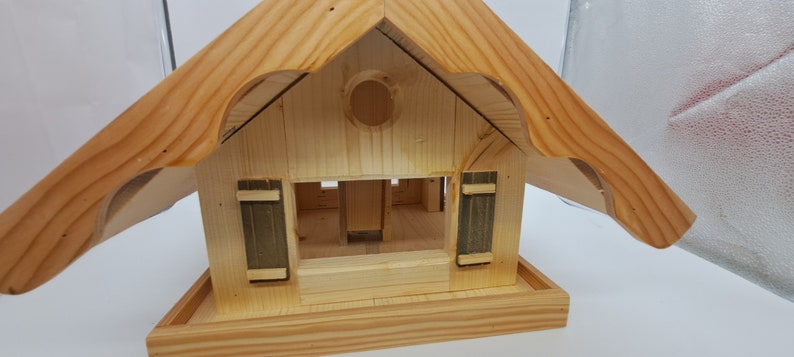 May include: Wooden birdhouse with a pitched roof and a small opening for birds to enter. The birdhouse has a small platform for birds to perch on.