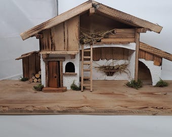 May include: A wooden nativity scene with a small, white-walled house with a brown door and a ladder. The house is on a wooden base with a brown, weathered finish.