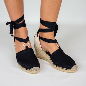 Handmade high-wedge espadrilles in black cotton with hoop of metal and black ribbons.