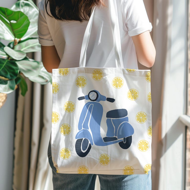 May include: White tote bag featuring a blue scooter illustration and yellow lemon slices. The bag has a simple design with a light background and a repeating pattern of lemon slices. The scooter is a light blue color.