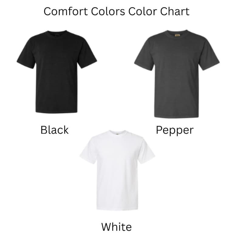 May include: Comfort Colors Color Chart featuring three short-sleeve t-shirts arranged in a triangular layout. The top left shirt is black, the top right shirt is pepper gray, and the bottom center shirt is white. Each shirt is labeled accordingly.