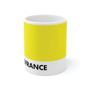 May include: White ceramic mug with a yellow band and black text that reads "TOUR DE FRANCE MAILLOT JAUNE".