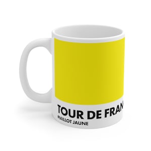May include: White ceramic mug with a yellow background and black text that reads "TOUR DE FRANCE MAILLOT JAUNE".