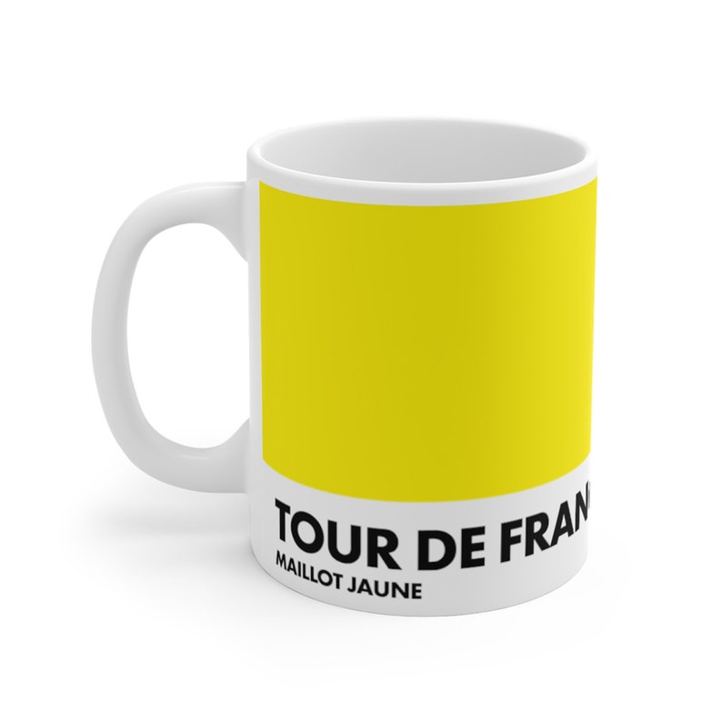May include: White ceramic mug with a yellow background and black text that reads "TOUR DE FRANCE MAILLOT JAUNE".