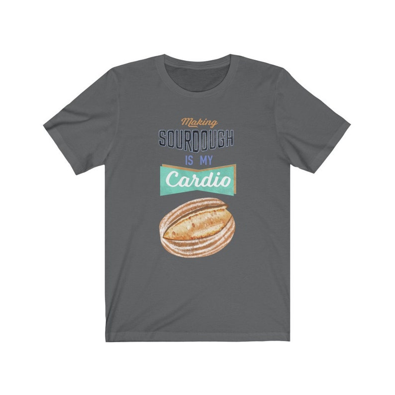 May include: A dark gray t-shirt with the text "Making sourdough is my cardio" in a vintage style font. A watercolor illustration of a sourdough loaf is below the text.