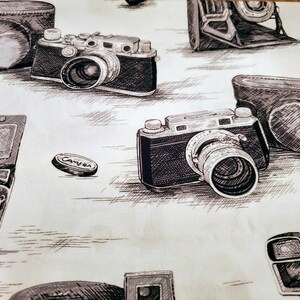 Może przedstawiać: Wz&oacute;r tapety w stylu vintage z r&oacute;żnymi rodzajami aparat&oacute;w fotograficznych, w tym aparatem 35 mm, dalmierzem i vintage'owym aparatem filmowym. Aparaty są narysowane w czerni i bieli na jasnobeżowym tle.