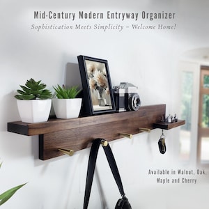 May include: A dark wood mid-century modern entryway organiser with a shelf holding two small potted plants, a framed picture, and a vintage camera. It has brass hooks and the text "Mid-Century Modern Entryway Organizer".