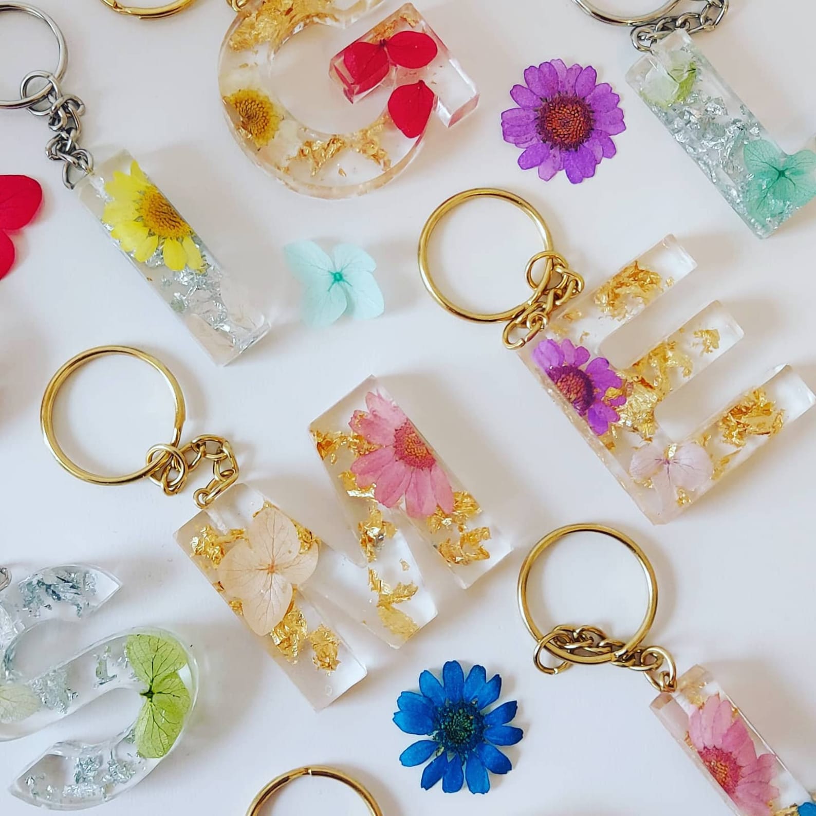 Crystal transparent resin, actual pressed flowers, and metallic leaf are used to make these handcrafted keyrings
