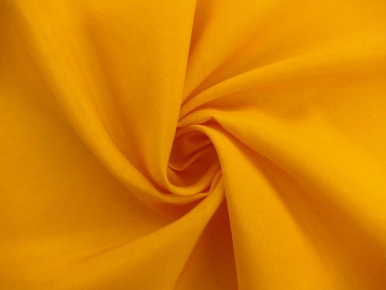 May include: A bright yellow fabric with a smooth texture. The fabric is folded and draped, creating a soft, flowing look.