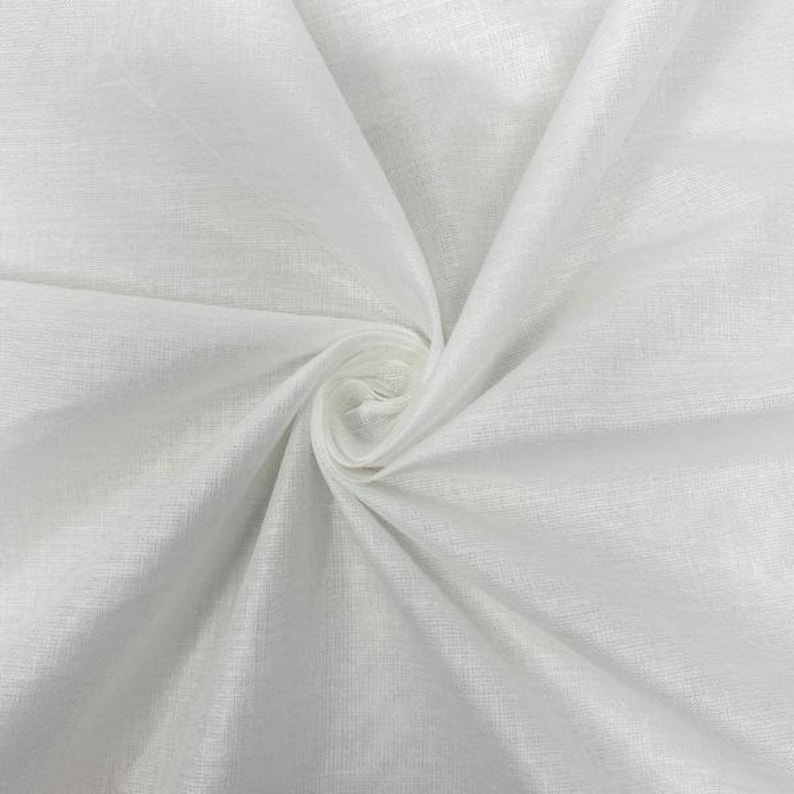May include: White fabric with a smooth, slightly textured surface. The fabric is folded and draped, creating soft folds and curves.
