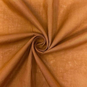 May include: A close-up of a piece of fabric in a warm brown color. The fabric is soft and has a slightly textured surface.