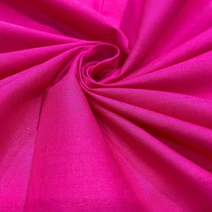 May include: A close-up of a vibrant pink fabric with a smooth, silky texture. The fabric is folded and draped, creating a soft, flowing effect.
