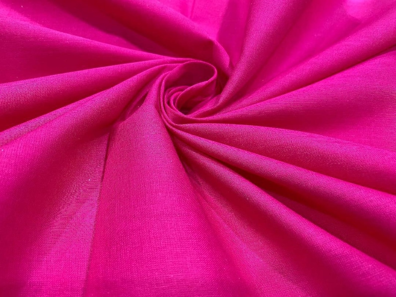 May include: A close-up of a vibrant pink fabric with a smooth, silky texture. The fabric is folded and draped, creating a soft, flowing effect.
