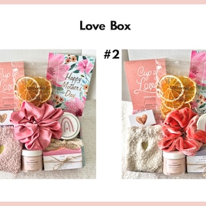 May include: Two gift boxes filled with various items, including a pink and a red hair scrunchie, a white fuzzy sock, a small jar of cream, a bar of soap, dried orange slices, and a card that says "Happy Mother's Day".