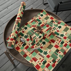 Puede incluir: Papel de regalo navideño con un diseño de patchwork en rojo, verde y beige. Un regalo envuelto con una cinta marrón está sobre el papel, junto con un rollo del mismo papel, tijeras y cinta adhesiva.