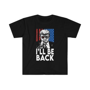以下が含まれることがあります： 「I'LL BE BACK」のテキストと、指を指す男性のグラフィックが特徴の黒いTシャツ。デザインにはアメリカ国旗が組み込まれており、男性はサングラスをかけています。