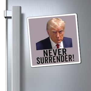 May include: A square magnet with a photo of a man with blonde hair and a serious expression. The man is wearing a dark suit and red tie. The text "NEVER SURRENDER!" is printed in black letters below the photo.