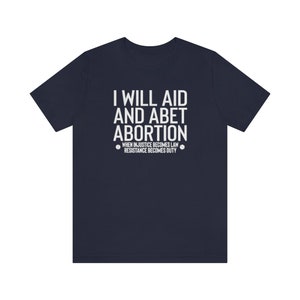 May include: A navy blue t-shirt with the text "I will aid and abet abortion. When injustice becomes law, resistance becomes duty." printed in white.