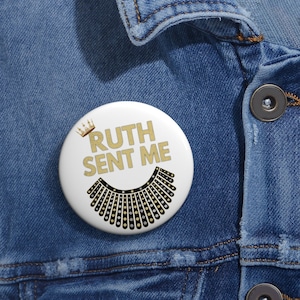 May include: A white button with a gold crown, the text "RUTH SENT ME" in gold letters, and a black and gold collar design.