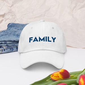 Puede incluir: Gorra de béisbol blanca con la palabra "FAMILY" bordada en azul en la parte delantera.