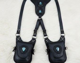 May include: Black leather harness with two pouches and turquoise-colored stone accents. The harness features adjustable straps, metal rings, and decorative stitching. A unique accessory for cosplay or alternative fashion.