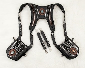 May include: Black leather harness with decorative stitching, silver studs, and turquoise-colored stone accents. Includes two detachable pouches and two adjustable straps with silver clasps. The harness is designed with a western or bohemian aesthetic.