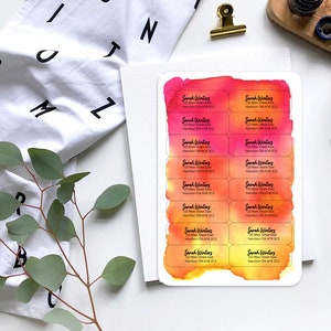 May include: A sheet of 12 watercolor-style return address labels with the text "Sarah Winters" and contact information. The labels are printed on white paper with a pink and orange watercolor background.