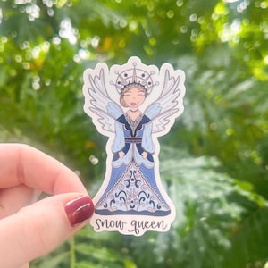 May include: A sticker featuring a cartoon illustration of a snow queen wearing a blue and white dress with a crown and wings. The text "snow queen" is printed below the illustration.