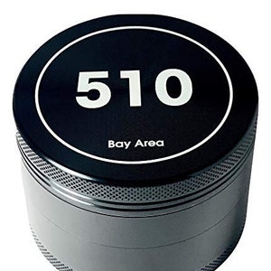 Könnte beinhalten: Ein silberner Grinder mit einem schwarzen Deckel. Der Deckel hat einen weißen Kreis mit der Nummer "510" und dem Text "Bay Area" darauf gedruckt.