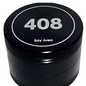 May include: A black, cylindrical grinder with a silver rim and the number "408" in silver. The text "Bay Area" is below the number. The grinder has a textured bottom.