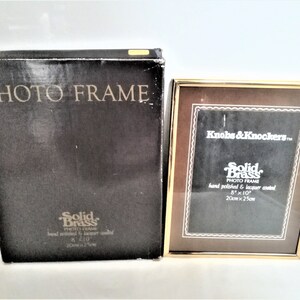Könnte beinhalten: Ein goldfarbener Messing-Fotorahmen mit braunem Passepartout und schwarzer Box. Der Rahmen ist 20cm x 25cm groß. Auf der Box steht "PHOTO FRAME" und "Solid Brass".