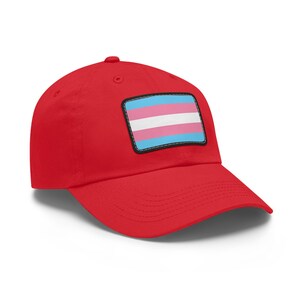 May include: Red baseball cap with a blue, pink, and light blue transgender pride flag patch.