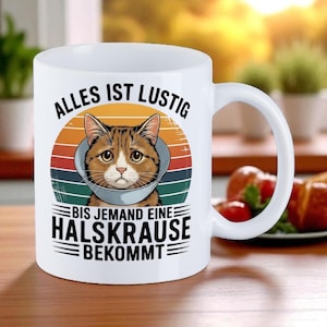 Könnte beinhalten: Weißer Keramikbecher mit einem Vintage-Grafik einer Katze mit Halskrause, vor einem Retro-Sonnenuntergangsdesign. Der Becher trägt den deutschen Text "Alles ist lustig bis jemand eine Halskrause bekommt."