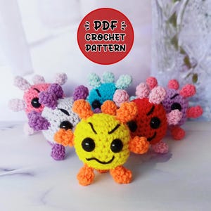 May include: A crochet pattern for making a set of colorful virus plush toys. The pattern is available as a PDF download. The toys are made in various colors, including yellow, red, blue, purple, and white. Each toy has a unique facial expression.