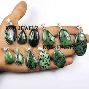 Könnte beinhalten: Zehn grüne und schwarze Edelstein-Anhänger mit silbernen Einstellungen. Die Anhänger sind in Form von Tropfen und Ovalen. KGN JEWELZ ist auf dem Bild gedruckt.