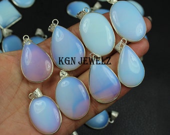 May include: A collection of opal gemstone pendants with silver settings. The pendants are in various shapes, including teardrop and oval. The opals are a milky white color with iridescent flashes of blue and pink.