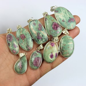 May include: A collection of ten green and pink gemstone pendants with silver settings. The pendants are oval and teardrop shaped and feature a mottled green and pink pattern.