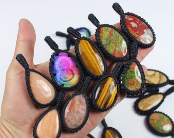 May include: A collection of colorful gemstone pendants with black macrame cord. The stones include tiger's eye, sunstone, and a variety of other colorful stones.