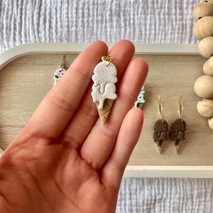 May include: White and brown ice cream cone shaped earrings with a gold accent. The earrings are made of polymer clay and are handmade.