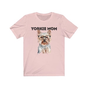 May include: Pink t-shirt with the text "Yorkie Mom" and a watercolor illustration of a Yorkshire Terrier wearing glasses.