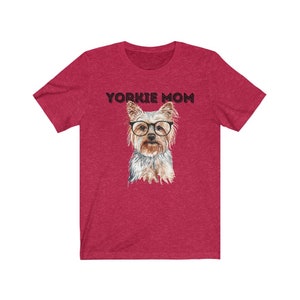 May include: Red short-sleeved t-shirt with the text "Yorkie Mom" in black lettering and a watercolor illustration of a Yorkshire Terrier wearing glasses.
