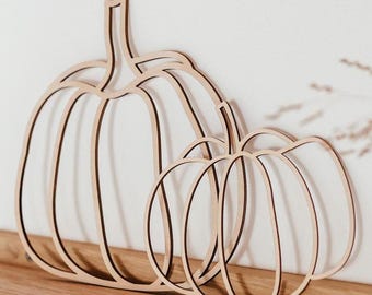 Puede incluir: Corte de madera de tres calabazas de diferentes tamaños. Las calabazas están superpuestas, creando un efecto de capas. Las calabazas son de color marrón claro.