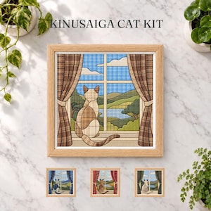 Könnte beinhalten: Ein Kinusaiga-Katzen-Set mit einem gerahmten, quadratischen Stoffbild, das eine Katze auf einer Fensterbank vor einer Landschaft zeigt. Die Szene umfasst braune karierte Vorhänge, einen blauen Himmel und grüne Hügel. Drei kleine Varianten sind abgebildet.