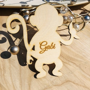 Könnte beinhalten: Holz-Platzkarte in Form eines Affen mit dem Namen "Gabi" auf der Vorderseite graviert.