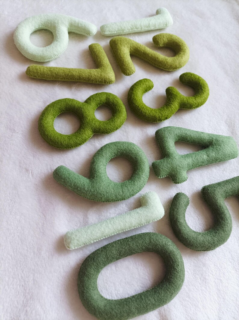 May include: Felt numbers in shades of green and white, from zero to nine. The numbers are arranged in a random order.