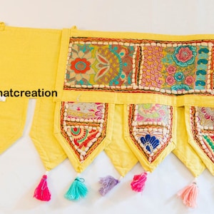 Op de afbeelding: Een gele stoffen valance met kleurrijke geborduurde patchworkdetails en kwastjes. De valance heeft een gegolfde rand en is versierd met verschillende bloemenpatronen. De tekst "jannatcreation" is zichtbaar op de valance.